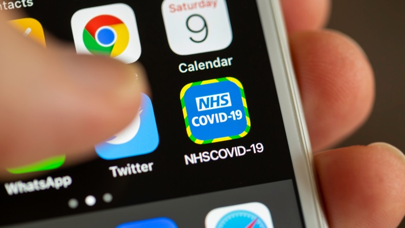 BATH, UK - MAY 9, 2020 : Close-up of the NHS COVID-19 contact tracing app on an iPhone screen with a thumb hovering above it. The app is used to track contact between people with Coranavirus.