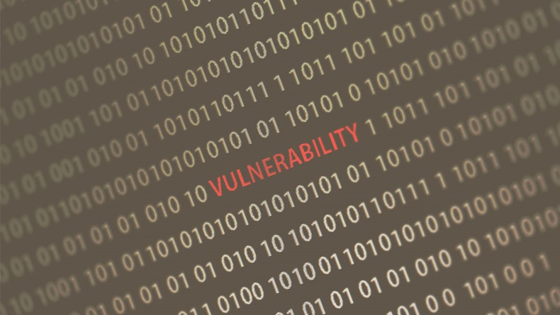 'Vulnerability' word in the middle of the computer screen surrounded by numbers zero and one. Image is taken in a small angle. Image has a vintage effect applied.