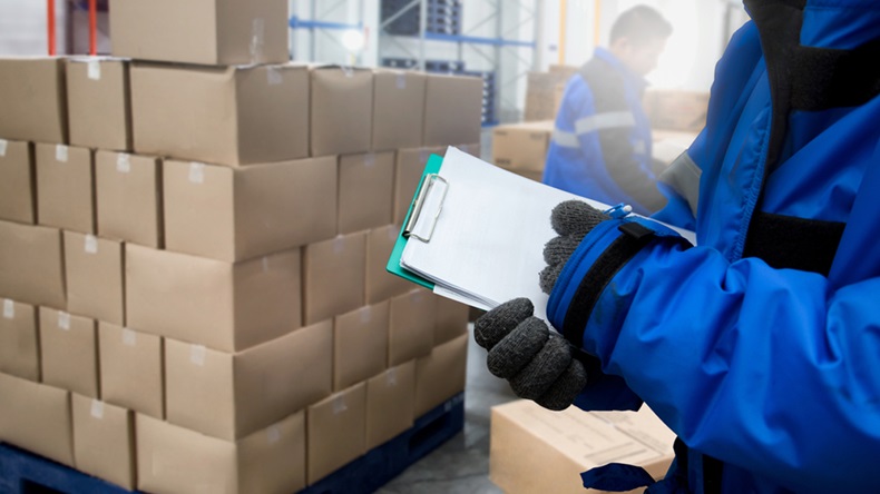 Close-Up shooting hand of worker with clipboard checking goods in freezing room or warehouse. Export-Import Logistics system concept - Image 