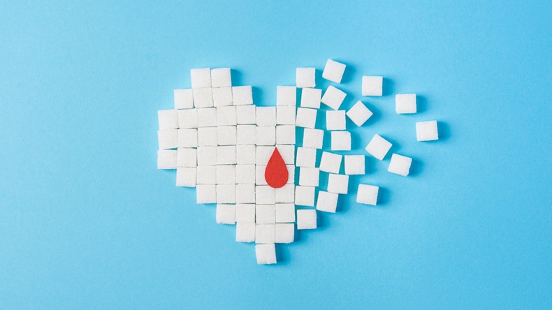 the drop of blood on broken heart made of pure white cubes of sugar isolated on blue background, World diabetes day, November 14 - Image 