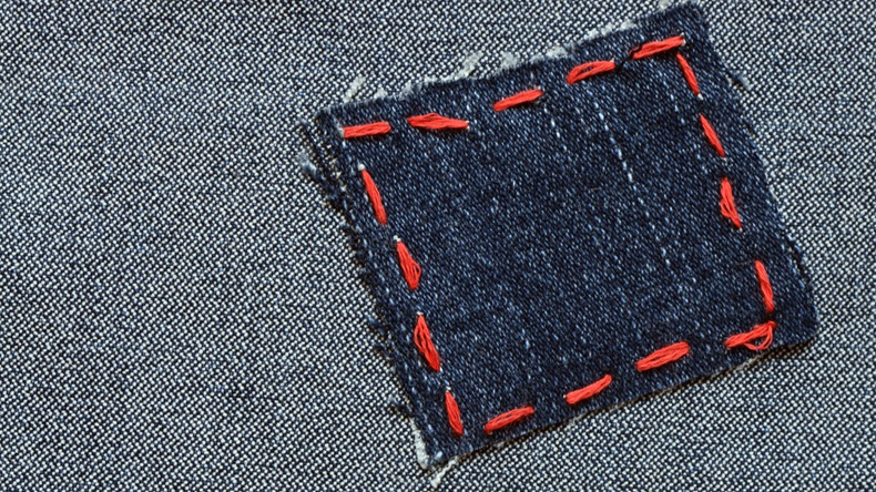 Patch with red thread attached on jeans textured - Image 
