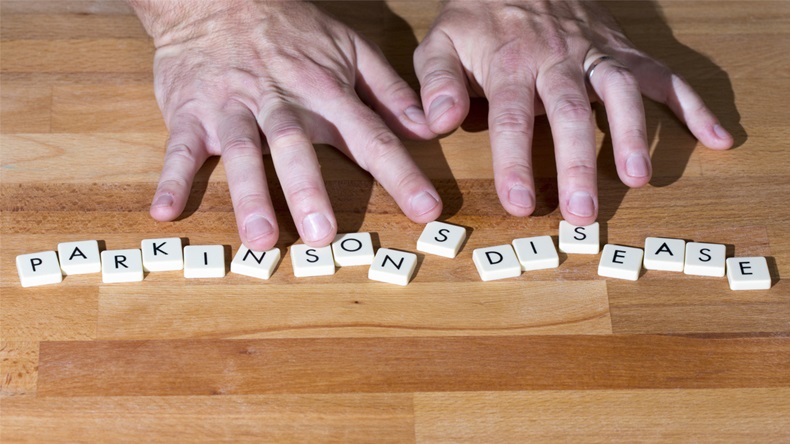 Parkinson's disease text on a wooden table. Shaking fingers touches the letters. - Image 