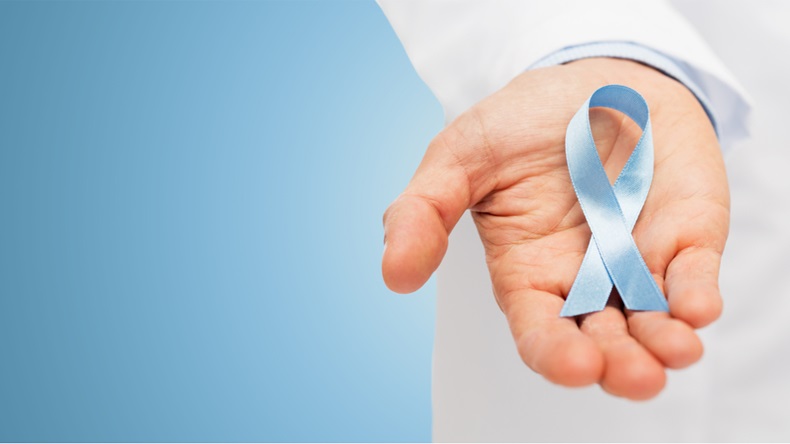 healthcare, profession, people and medicine concept - close up of male doctor hand holding sky blue prostate cancer awareness ribbon over blue background - Image 