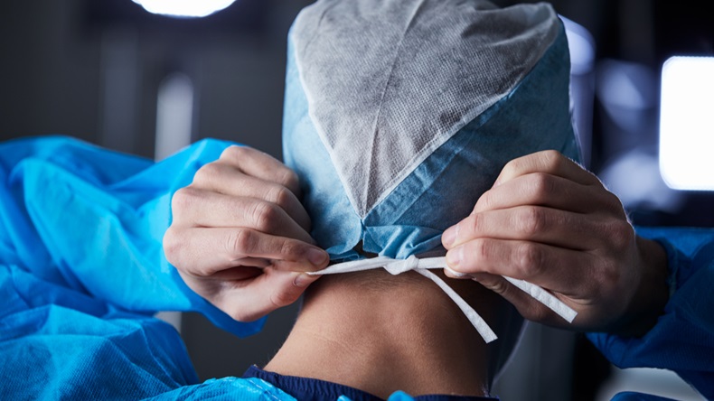 Surgeon tying surgical cap in preparation, back view