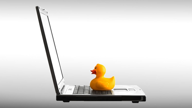 Laptop and rubber yellow duck toy isolated on white background
