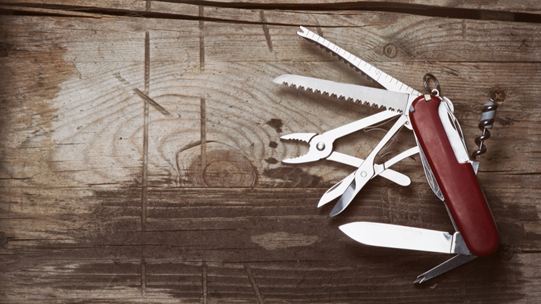 old Swiss knife on a wooden background. Top view with copy space