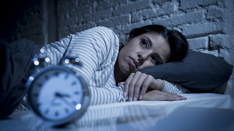 woman at home bedroom lying in bed late at night trying to sleep