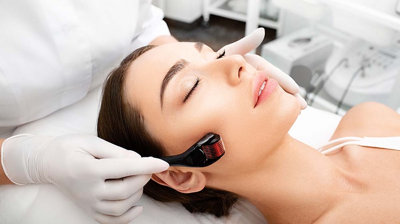 Beautician doing skin treatment using a microneedle derma roller. Woman getting procedure skincare, with mezzo skin roller.