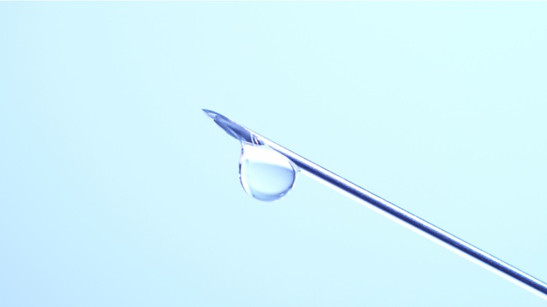 Vaccine dripping from sterile needle syringe