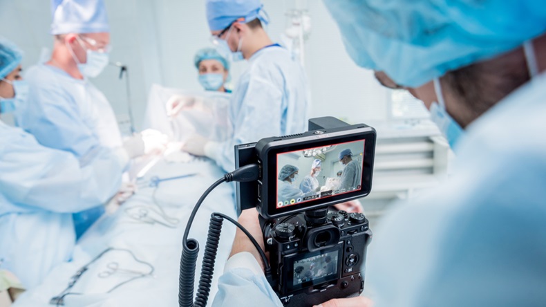 A videographer shoots the surgeon and assistants in the operating room with surgical equipment.