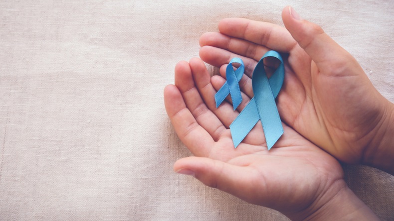 Hands holding blue ribbons for prostate cancer awareness.