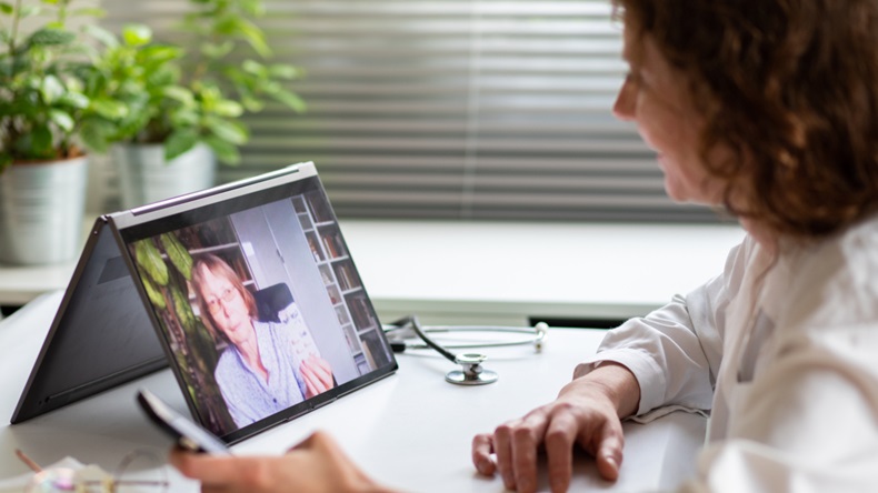 Elderly woman communicating with doctor through computer; telemedicine concept
