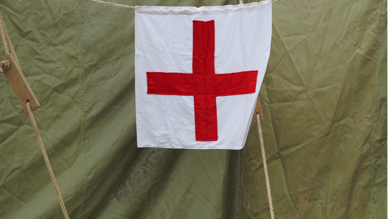 The sign of the red cross on a canvas army tent. Mobile military hospital.