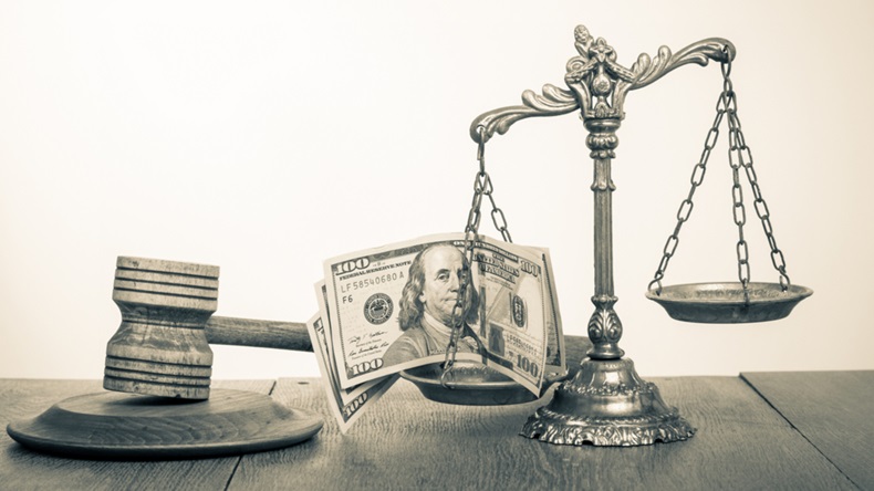 Greyscale money on scales of justice resting near a gavel