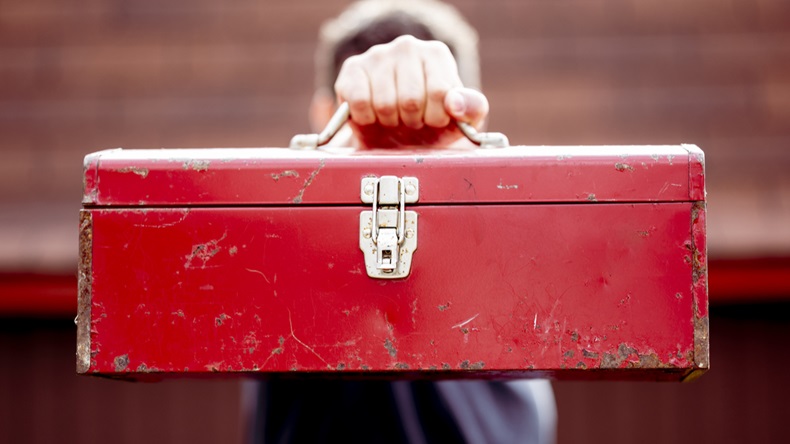 A closeup shot of a male holding a toolbox.