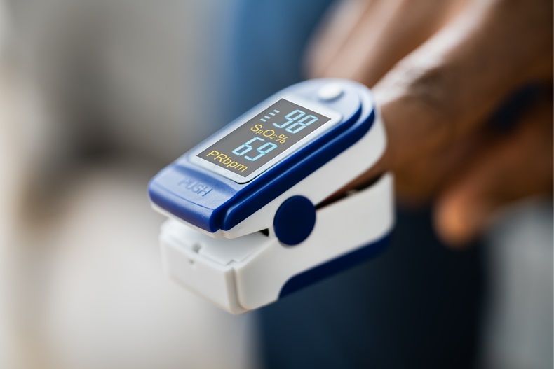 A pulse oximeter clipped onto the finger of an African-American person. 