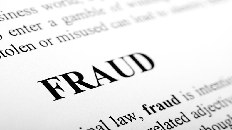 The word "fraud" and its definition are shown in black text on white paper, using selective focus. 