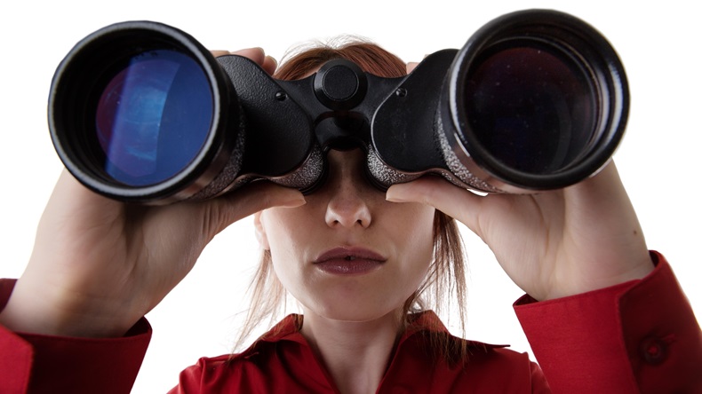 close up image of woman looking through binoculars 