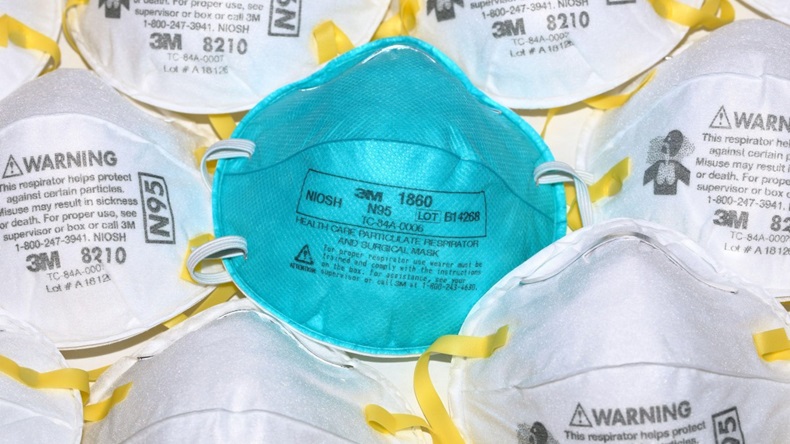 A surgical N95 respirator mask among a sea of construction N95 respirators and face masks