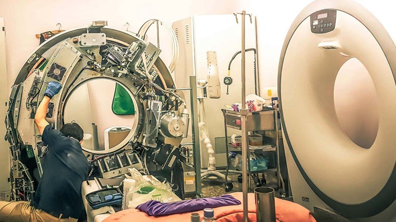 A maintenance engineer repairing and checking a CT scanner machine in a hospital
