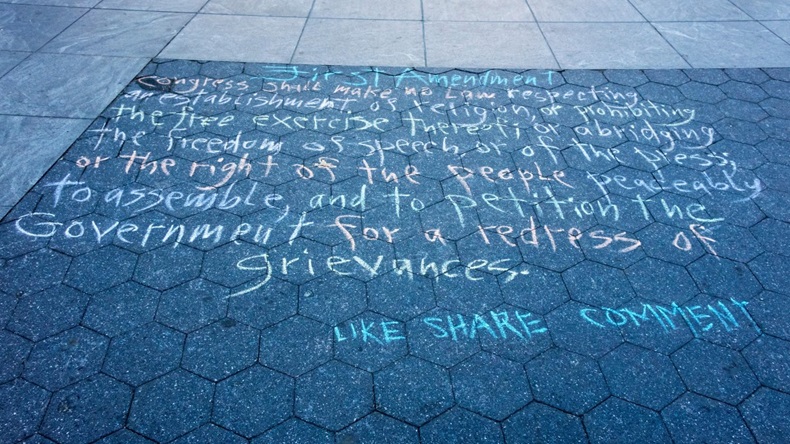 Text of the First Amendment written in colored chalk on a New York sidewalk.