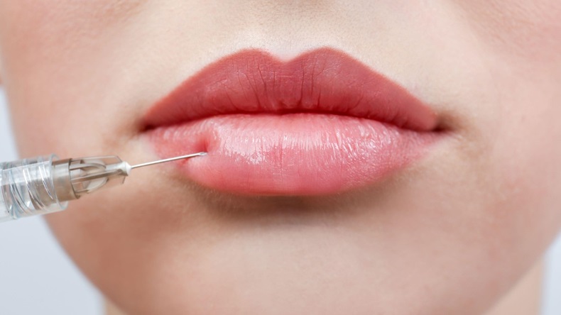 Closeup of young woman receiving filler injection in lips