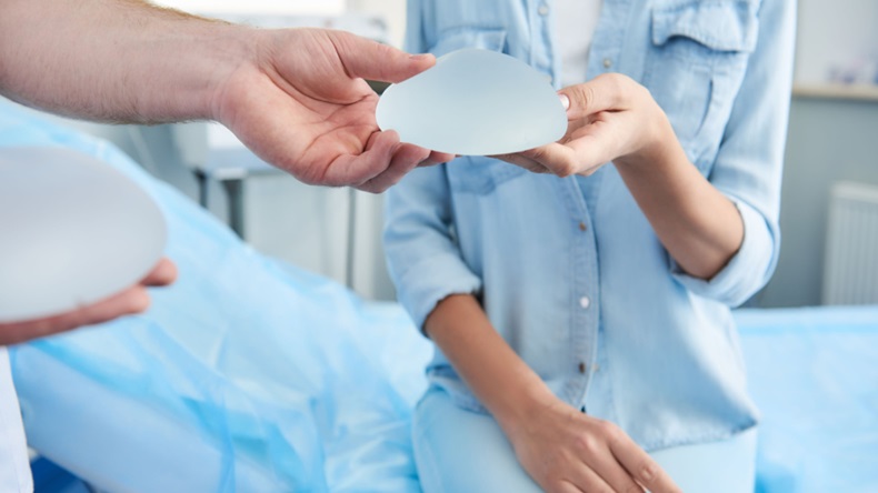 Close-up photo of doctor showing silicone implant to woman during consultation .
