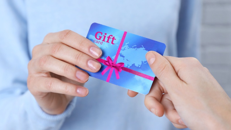 Woman's hand giving gift card to friend. 