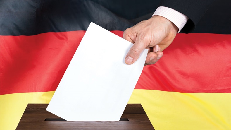 Close-up Of A Person Putting Vote In A Ballot Box In Front Of German Flag