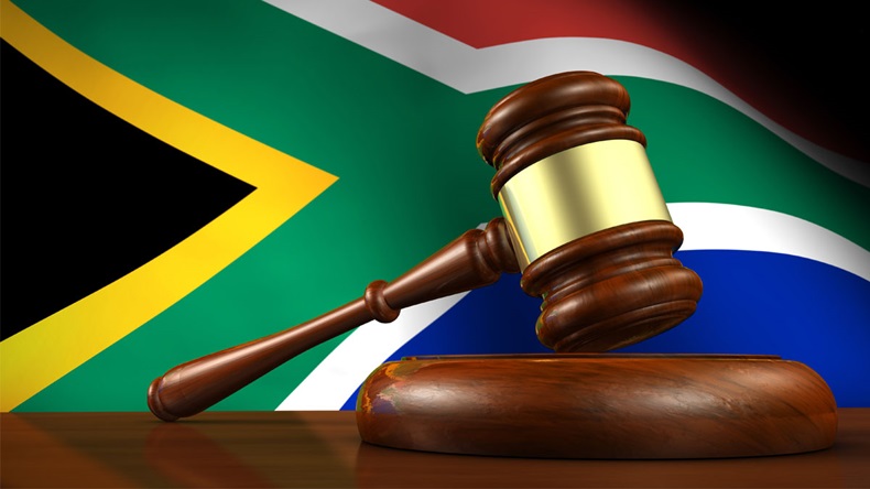 South Africa law and justice concept with a 3d render of a gavel on a wooden desktop and the South African flag on background.