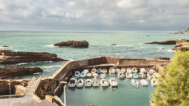 boats are safely tucked for a stone wall from the waves of the ocean/boats in a quiet Harbor on the Atlantic coast of Spain