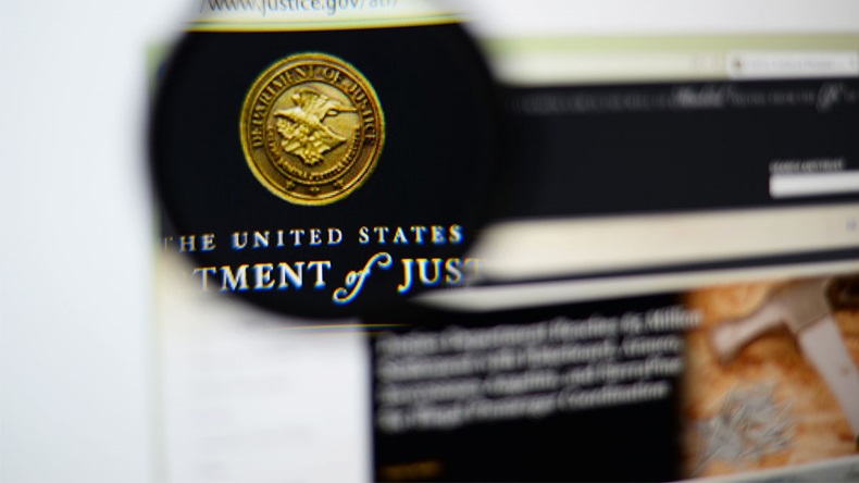 LISBON, PORTUGAL - December 9, 2014: Photo of the United States Department of Justice (DOJ) homepage on a monitor screen through a magnifying glass. 